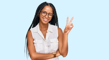 Gündelik kıyafetler ve gözlük takan güzel İspanyol kadın kameraya gülümseyen ve zafer işareti yapan. İki numara.. 