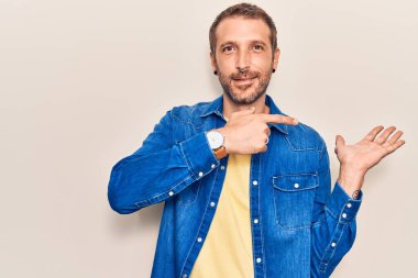 Gündelik kıyafetler giyen genç yakışıklı adam kameraya hayret ediyor ve gülümsüyor.. 