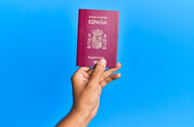 İspanyol pasaportlu bir adamın elleri mavi arka planda..
