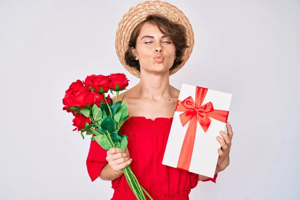 年轻的惊慌失措的女人带着礼物和一束鲜花迎接结婚周年纪念日 看着摄像机吹拂着一个美丽而性感的吻 爱的表达 — 图库照片