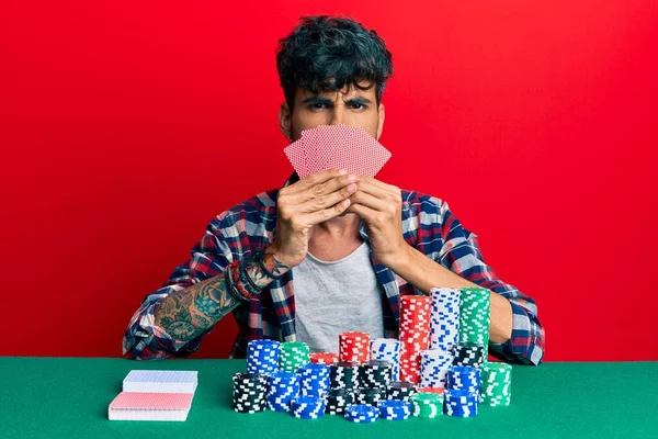 Jovem Hispânico Jogando Poker Cobrindo Rosto Com Cartões Céticos Nervosos — Fotografia de Stock