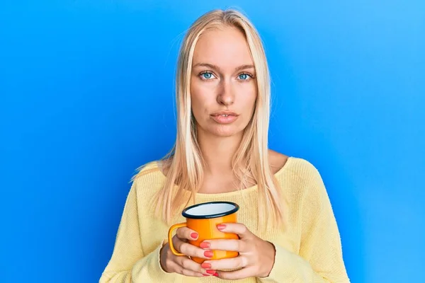 Młoda Blondynka Trzymająca Kawę Zrelaksowana Poważnym Wyrazem Twarzy Proste Naturalne — Zdjęcie stockowe