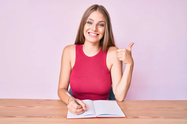 Joven Chica Caucásica Escribiendo Cuaderno Sentado Mesa Sonriendo Feliz Positivo — Foto de Stock