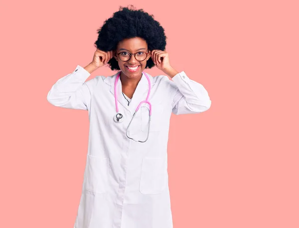 Junge Afroamerikanerin Arztkittel Und Stethoskop Lächelnd Mit Fingern Ohren Zuziehend — Stockfoto