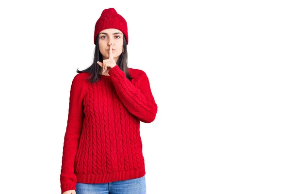 Młoda Piękna Dziewczyna Nosi Sweter Wełnianą Czapkę Prosząc Ciszę Palcem — Zdjęcie stockowe
