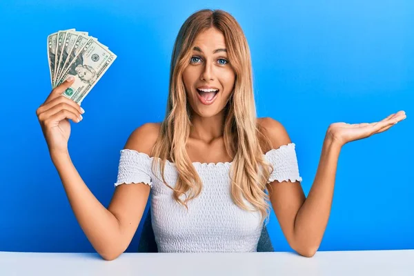 Piękna Blondynka Młoda Kobieta Trzyma Dolarów Banknotów Świętujących Osiągnięcie Szczęśliwym — Zdjęcie stockowe