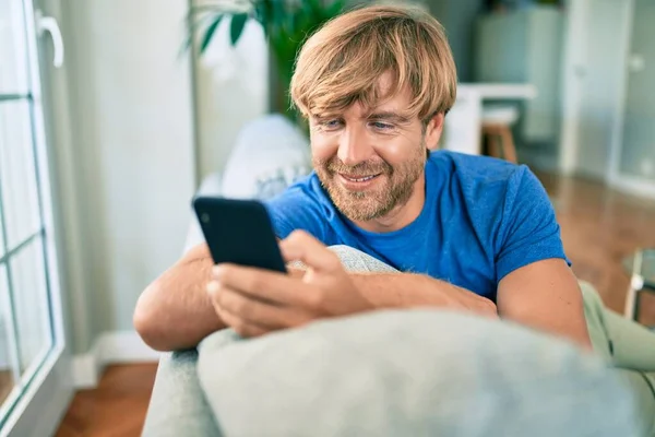 Middelbare Leeftijd Knappe Kaukasische Man Ontspannen Bank Thuis Met Smartphone — Stockfoto