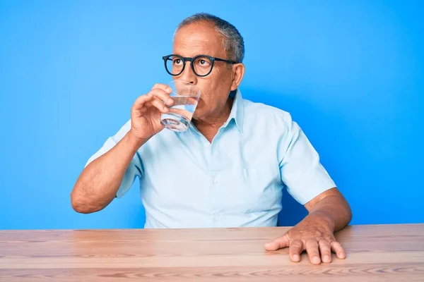 Pohledný Starší Muž Sedí Doma Stole Pije Sklenici Čerstvé Vody — Stock fotografie