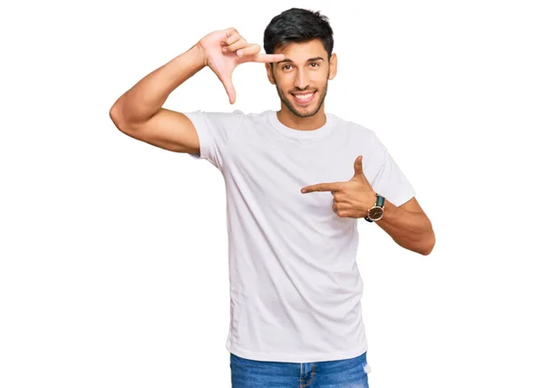 年轻英俊的男人穿着随意的白色T恤 微笑着 用手和手指做框架 脸上带着幸福的表情 创意与摄影概念 — 图库照片