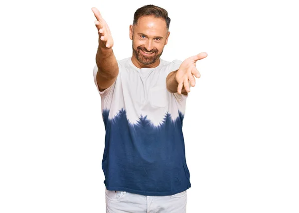 抱擁のために開いた腕で笑顔カメラを見てカジュアルなネクタイ染料のTシャツを着てハンサムな中年の男 幸せを受け入れる陽気な表情 — ストック写真