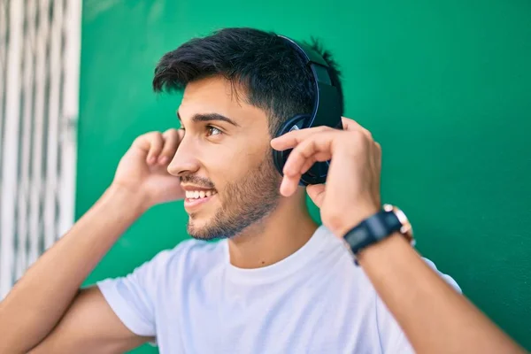 Jovem Latino Sorrindo Feliz Usando Fones Ouvido Apoiados Parede Cidade — Fotografia de Stock