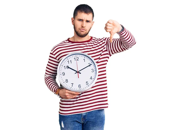Jovem Homem Bonito Segurando Relógio Grande Com Cara Irritada Sinal — Fotografia de Stock