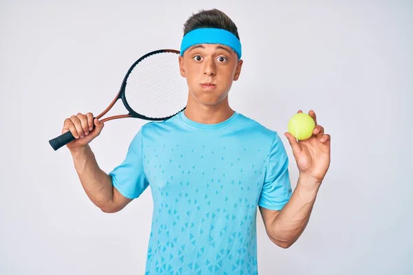 若いヒスパニック系の少年は面白い顔でラケットとボールの頬をむち打つ保持テニスをしている 空気を吸い込み空気を吸い込み — ストック写真