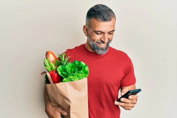 Hombre Guapo Mediana Edad Sosteniendo Bolsa Comestibles Usando Teléfono Inteligente —  Fotos de Stock