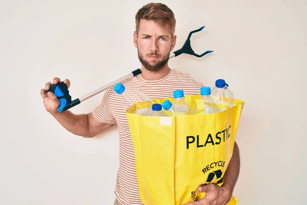 Młody Biały Mężczyzna Trzymający Worek Plastikowymi Butelkami Zbieraczem Odpadów Sceptyczny — Zdjęcie stockowe