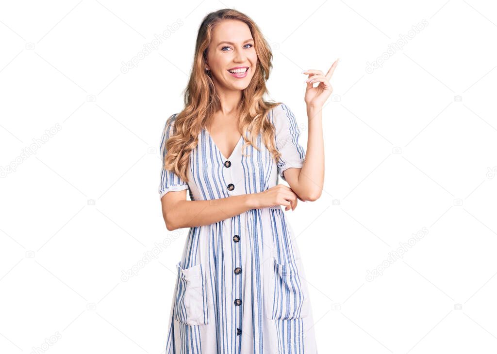 Young caucasian woman with blond hair wearing summer dress smiling happy pointing with hand and finger to the side 