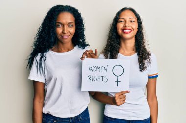 Afrika kökenli Amerikalı anne ve kız ellerinde kadın hakları pankartı var. Olumlu ve mutlu görünüyorlar. Ve gülümsüyorlar. 