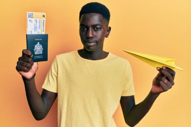 Elinde kağıt uçak ve pasaport tutan Afro-Amerikalı genç bir adam sıkıntılı ve endişeli, sinirli ve korkmuş bir şekilde ağlıyor. hüzünlü ifade. 