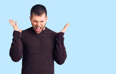 Gündelik kazak giyen genç, çılgın ve çılgın başarıyı kutlayan kollarını kaldırmış, gözlerini kapatmış heyecanlı çığlıklar atan yakışıklı bir adam. Kazanan konsept 