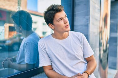 Şehrin duvarına yaslanmış, ciddi bir suratı olan beyaz bir genç..