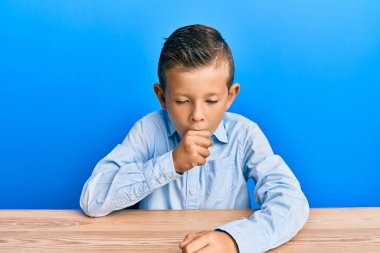 Kafkasyalı sevimli bir çocuk, günlük giysiler giymiş, kendini iyi hissetmiyor ve soğuk algınlığı veya bronşitin belirtisi olarak öksürüyor. sağlık hizmeti kavramı. 