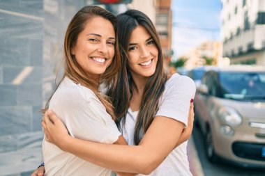 Güzel İspanyol anne ve kızı gülümseyerek şehirde mutlu mesut duruyorlar..