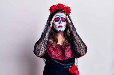 Genç bir kadın, ölü kostümünü beyazın üstüne giymiş, elleri kafasında, stresten baş ağrısı çekiyor. migren ağrısı. 