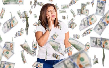 Orta yaşlı beyaz tişört giyen Latin bir kadın diş ağrısı ya da diş hastalığından dolayı ağızlarına acı dolu bir ifadeyle dokunuyor. dişçi