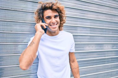 Genç İspanyol adam şehrin caddesinde akıllı telefondan konuşuyor.