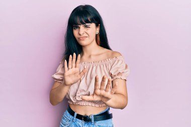 Gündelik kıyafetler giyen genç İspanyol kız tiksinti ifadesi takınıyordu. Tiksinti tepkisi yüzünden tiksinti ve korku ifadesi takınıyordu. Eller havada. 