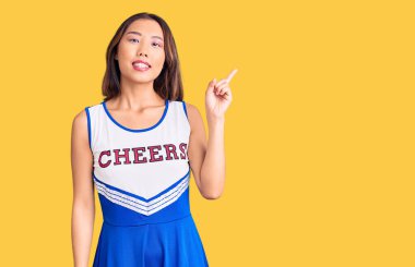 Yüzünde büyük bir gülümseme olan amigo kız üniforması giyen genç, güzel Çinli kız, kameraya el ile işaret ediyor.. 