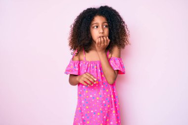 Kıvırcık saçlı, rahat giyimli, gergin ve elleri ağızda, tırnaklarını yiyen Afro-Amerikan çocuğu. anksiyete. 