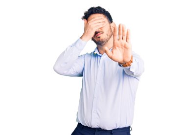 İş kıyafetleri giymiş genç İspanyol bir adam elleriyle gözlerini kapatıyor ve üzgün ve korku ifadeleriyle jest yapıyor. utangaç ve olumsuz kavram. 