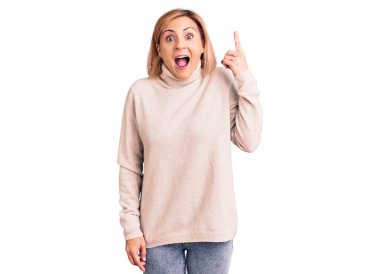 Gündelik kıyafetler giyen genç sarışın kadın başarılı bir fikri işaret ediyor. Heyecanlı ve mutlu. Bir numara.. 