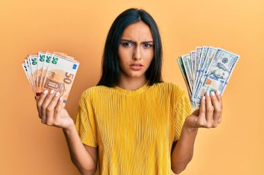 Elinde bir sürü dolar ve avro tutan esmer bir kadın. Hiçbir şeyden habersiz ve kafası karışmış bir ifade. şüphe kavramı. 
