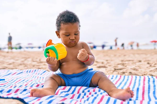 愛らしいアフリカ系アメリカ人の幼児はおもちゃで遊んでいます砂の上に座ってビーチ — ストック写真