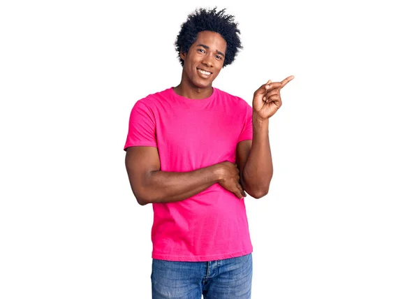 一个英俊的非洲裔美国男人 留着一头随意的粉色T恤 满面笑容 手指手画脚地朝旁边看去 — 图库照片