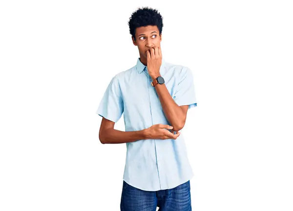 穿着休闲服的年轻的非洲裔美国人看上去很紧张 双手放在咬指甲的嘴上 焦虑问题 — 图库照片