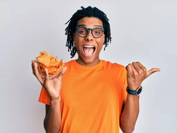 Joven Afroamericano Hombre Sosteniendo Nachos Patatas Fritas Apuntando Pulgar Hacia — Foto de Stock