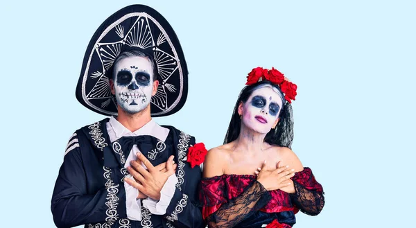 目を閉じて胸に手で笑顔を背景に死んだ衣装のメキシコの日を身に着けている若いカップルと顔に感謝のジェスチャー 健康の概念 — ストック写真