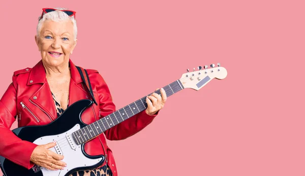 青い目と灰色の髪をしたシニアの美しい女性は 顔に幸せとクールな笑顔で電動ギターを演奏現代的な外観を身に着けています 運のいい人 — ストック写真