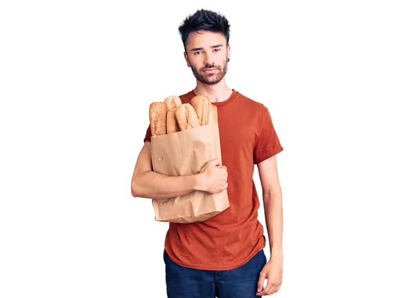 Young Hispanic Man Holding Paper Bag Bread Thinking Attitude Sober — Stock Photo, Image