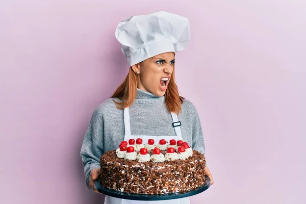 西班牙裔女厨师 手里拿着巧克力蛋糕 怒气冲冲地尖叫着 怒气冲冲地大叫着 愤怒和好斗的概念 — 图库照片