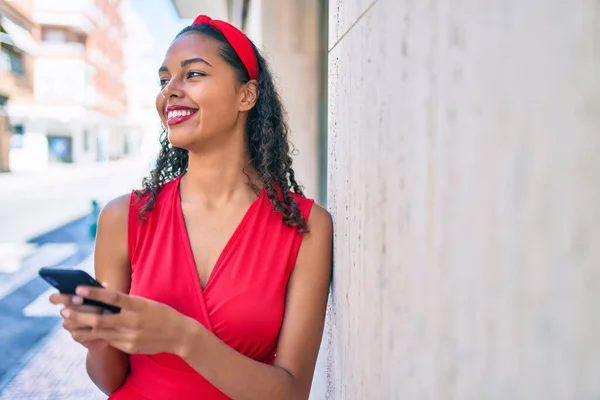 Joven Afroamericana Chica Sonriendo Feliz Usando Teléfono Inteligente Apoyado Pared —  Fotos de Stock