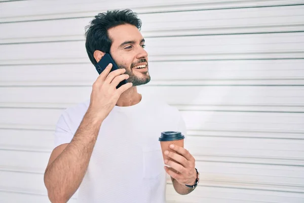 年轻的他的惊慌失措的男人高兴地微笑着 一边在智能手机上聊天 一边喝着咖啡 把咖啡都带走了 — 图库照片