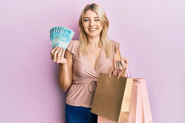 Junge Kaukasische Frau Mit Brasilianischen Echten Banknoten Und Einkaufstaschen Zwinkernd — Stockfoto