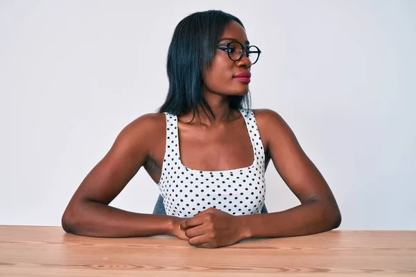 Mujer Afroamericana Joven Con Ropa Casual Gafas Sentadas Mesa Mirando —  Fotos de Stock