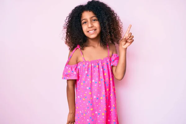顔に大きな笑顔でカジュアルなドレスを着ているアフリカ系アメリカ人の子供 カメラを見て側に手と指を指して — ストック写真