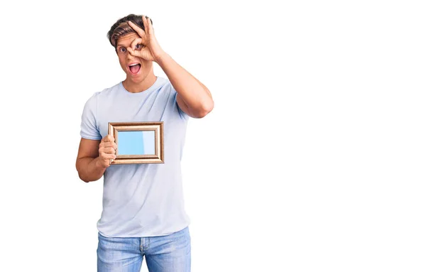 Jovem Homem Bonito Segurando Moldura Vazia Sorrindo Feliz Fazendo Sinal — Fotografia de Stock