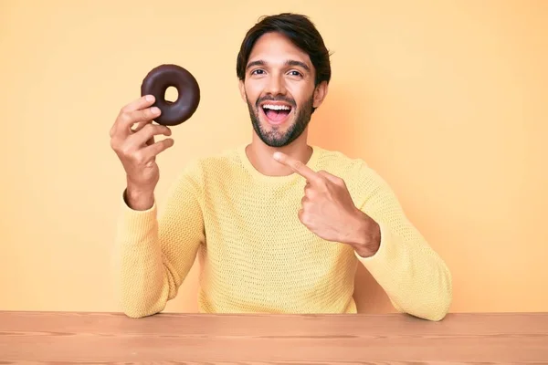 Όμορφος Ισπανός Που Κρατάει Ντόνατ Χαμογελώντας Χαρούμενος Δείχνοντας Χέρι Και — Φωτογραφία Αρχείου
